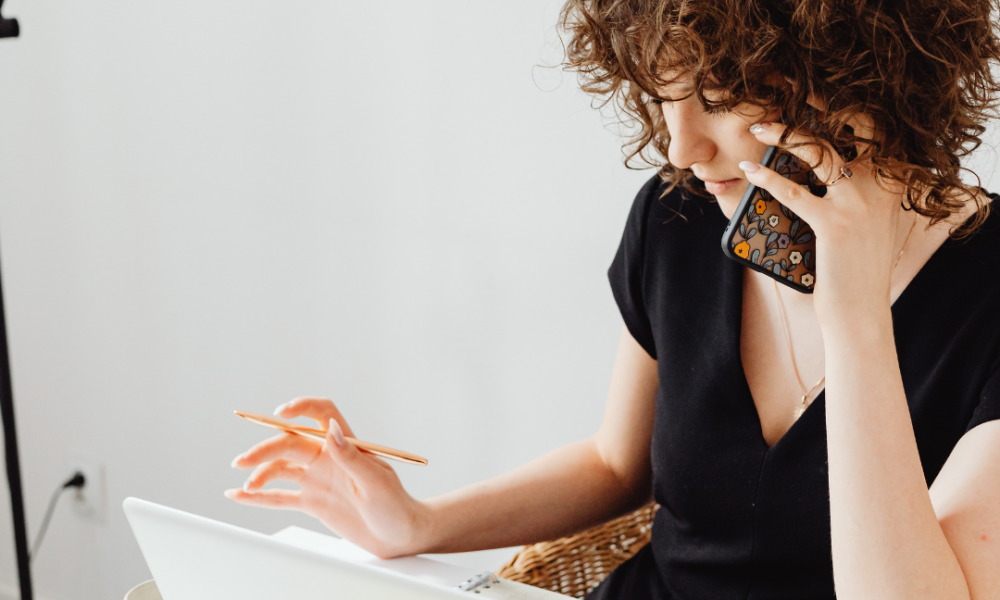 A woman working at a property brand, making a phone call in front of her laptop