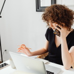A woman working at a property brand, making a phone call in front of her laptop