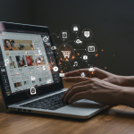 Hands typing on a laptop with elements floating from the screen, PR and Marketing