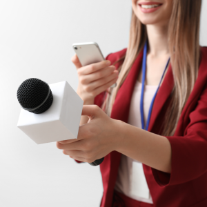 Female journalist pointing microphone whilst holding phone