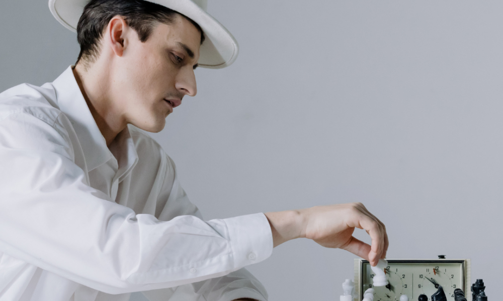 Man in white suit and hat making chess moves