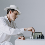 Man in white suit and hat making chess moves