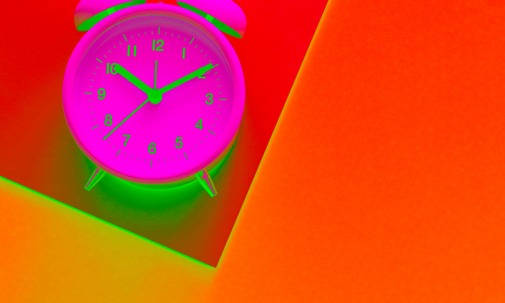 Neon pink alarm clock in orange backdrop