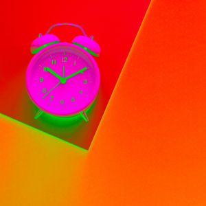 Neon pink alarm clock in orange backdrop